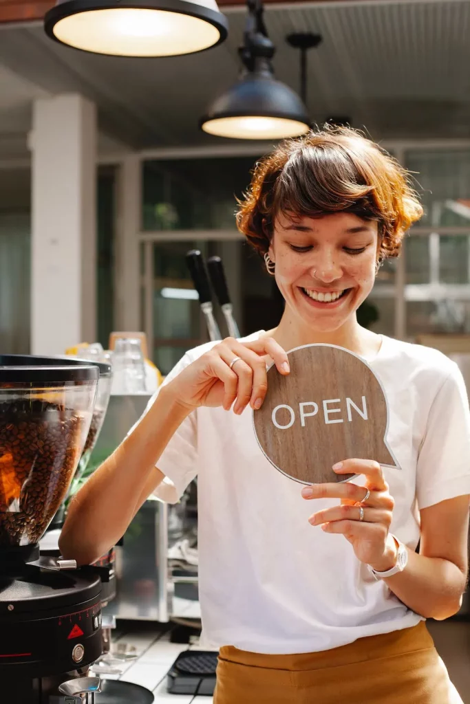 Restaurant owner with open sign smiling